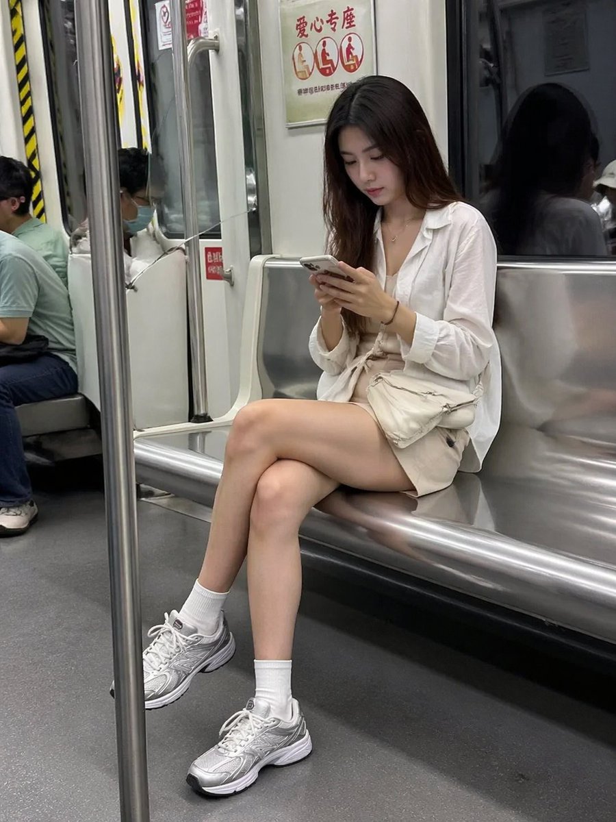 A beautiful woman on the subway looking down at her phone, candid street photography style. Natur...